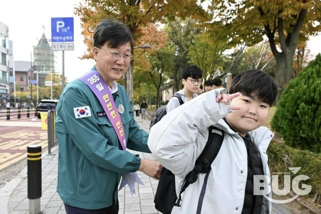 이민근 안산시장(사진 왼쪽)이 학현초등학교 앞에서 ‘스쿨존 어린이 교통안전 캠페인’을 진행하며 등교하는 어린이의 가방에 '홍이 키링'을 달아주고 있다.